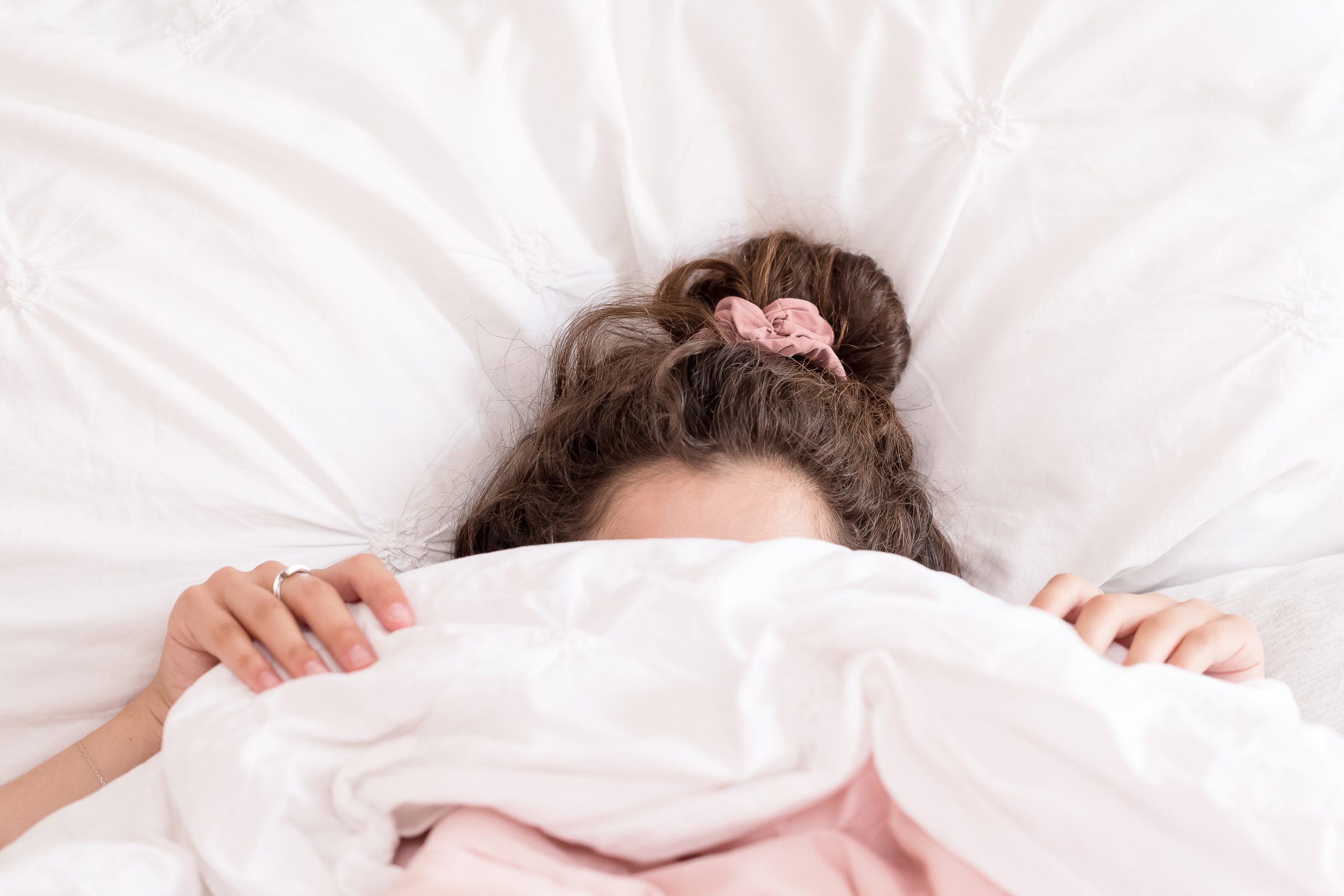 Woman hiding under a pink duvet