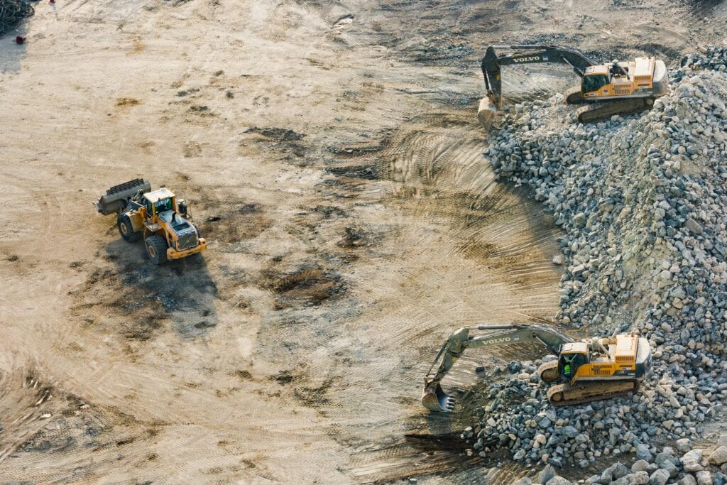 3 diggers digging up some land.
