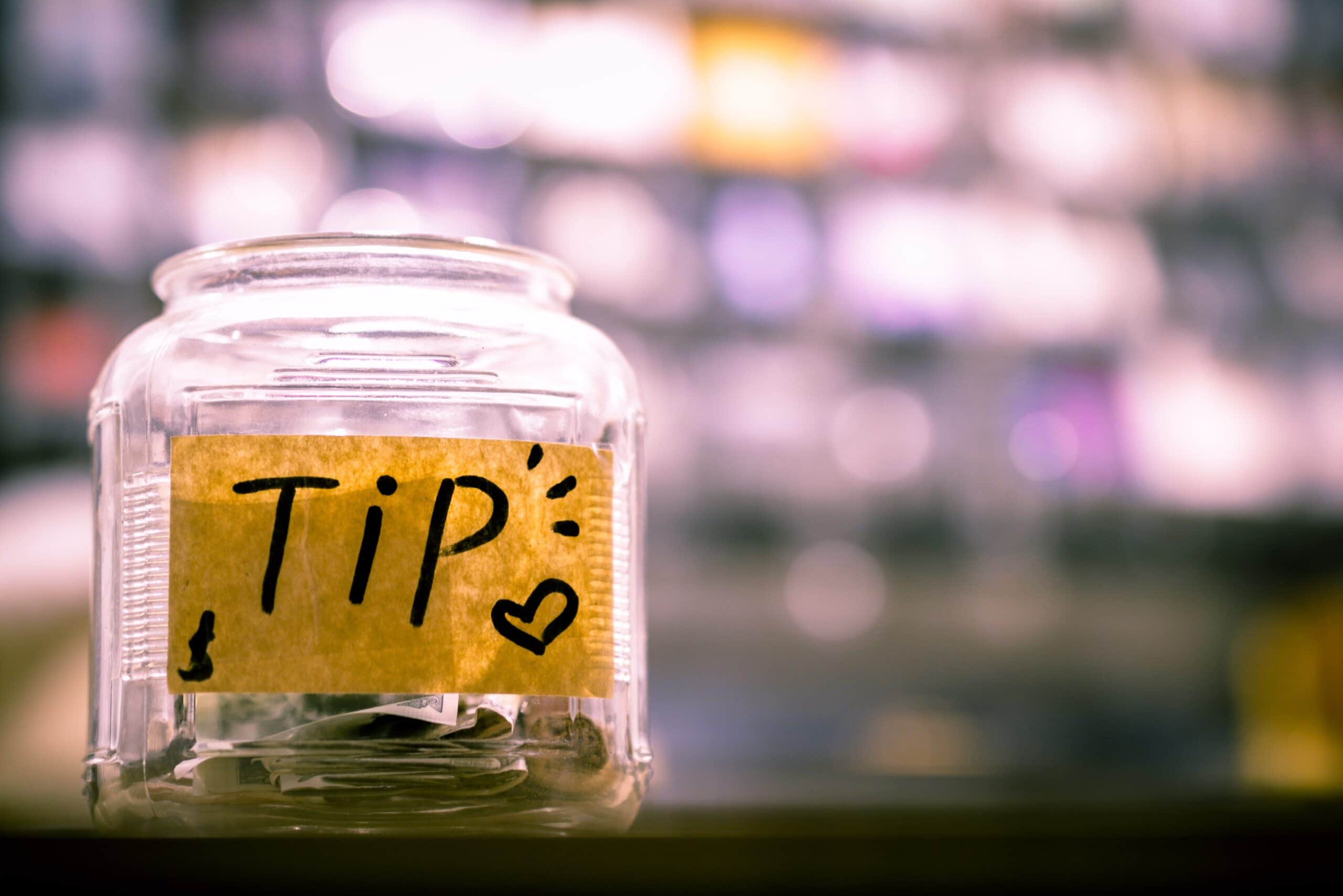 Cute jam jar filled with coins with a label that says TIP with a little heart.